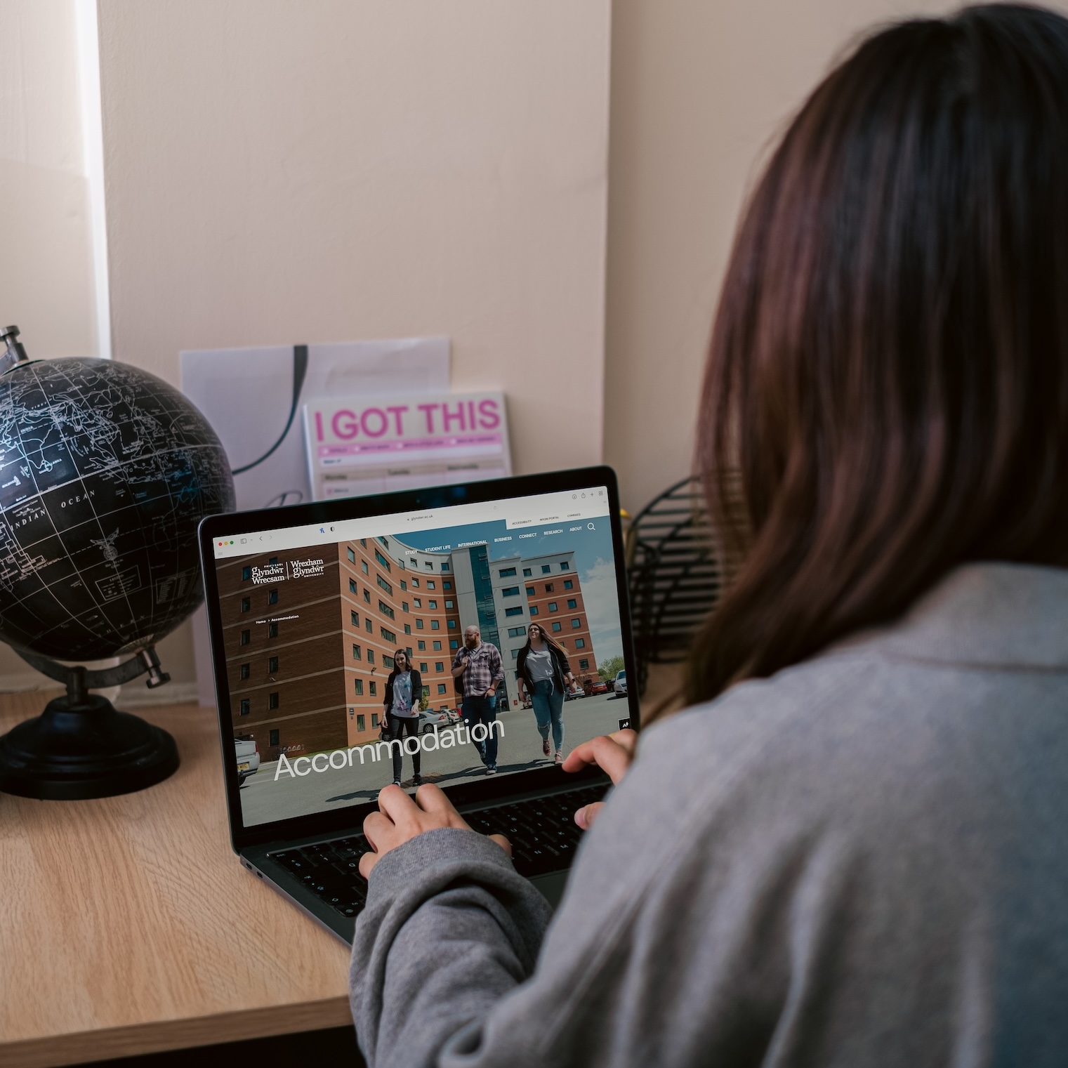 The back of a person sitting at a laptop that is viewing the Wrexham University website