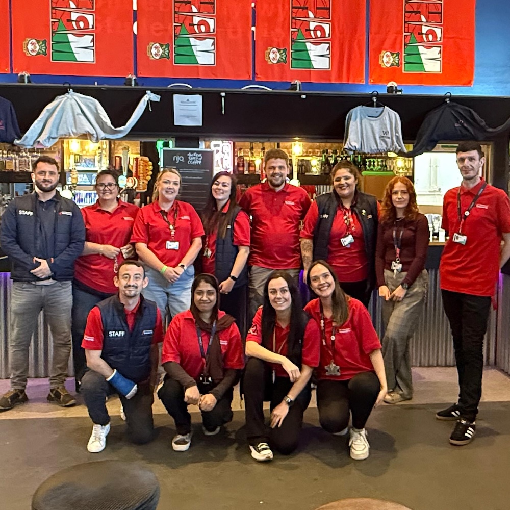 Group of twelve people all wearing red tops standing in a room with red banners